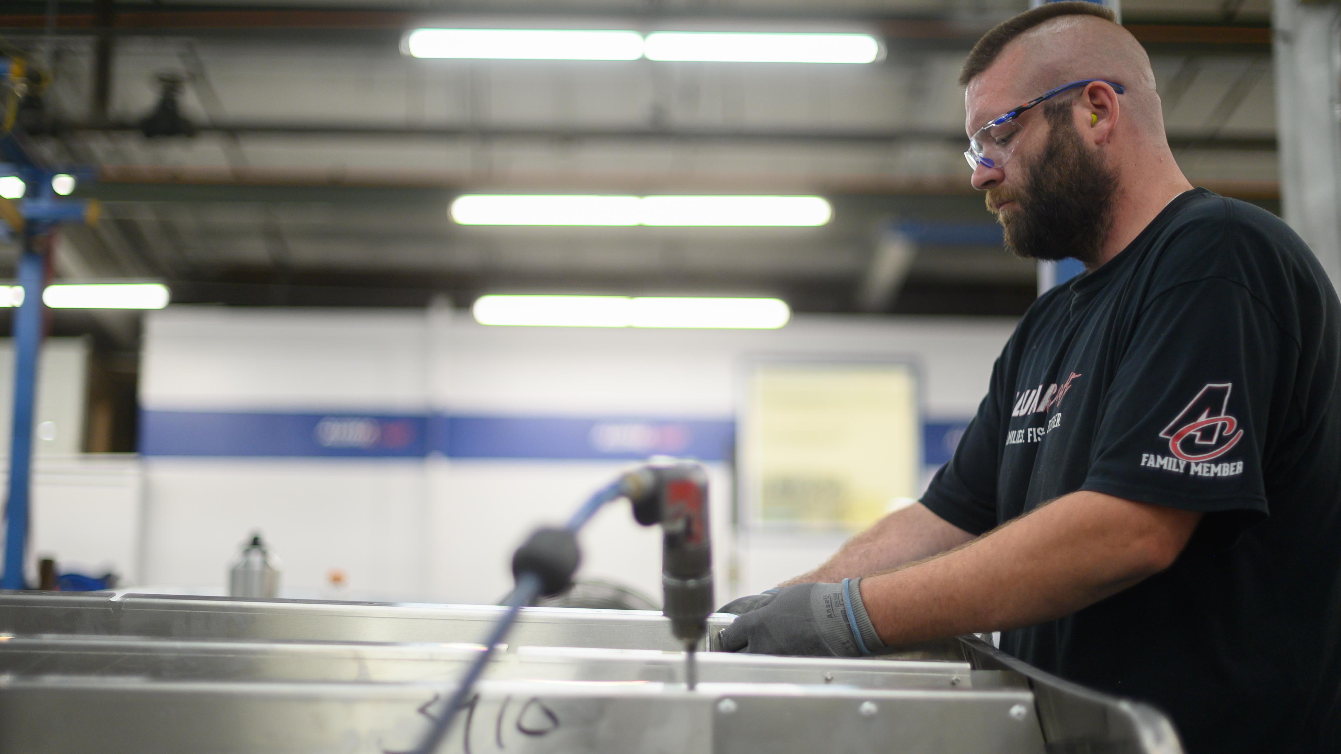 Man working on the aluminum hull of an Alumacraft boat