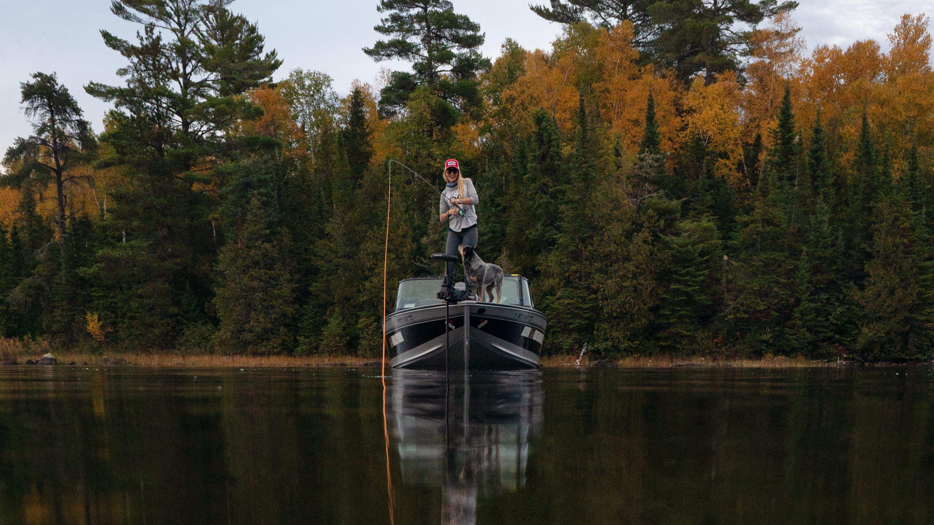 Femme pêchant à l'aube sur son bateau Alumacraft