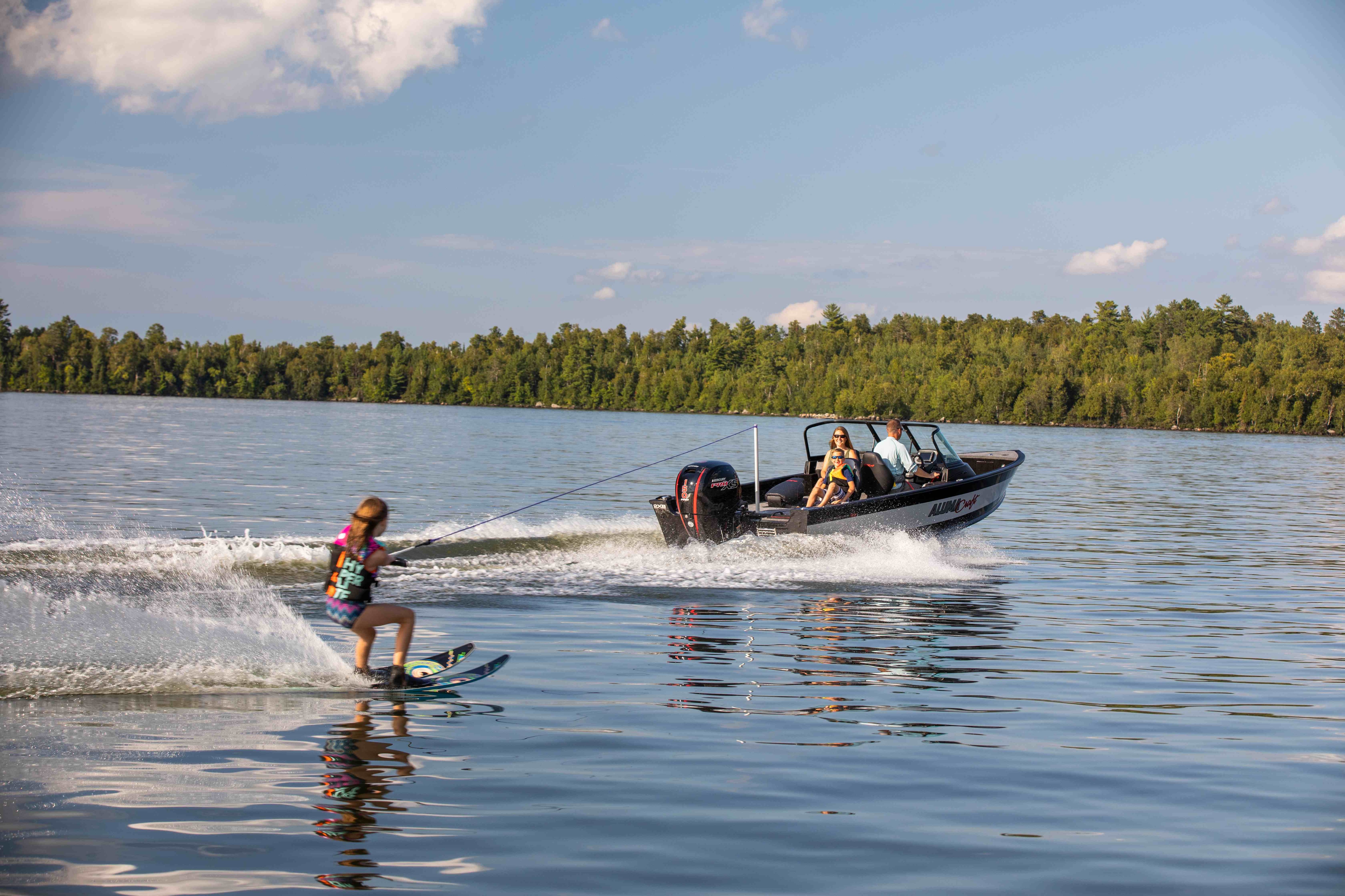 Garçon en ski nautique derrière un bateau en aluminium