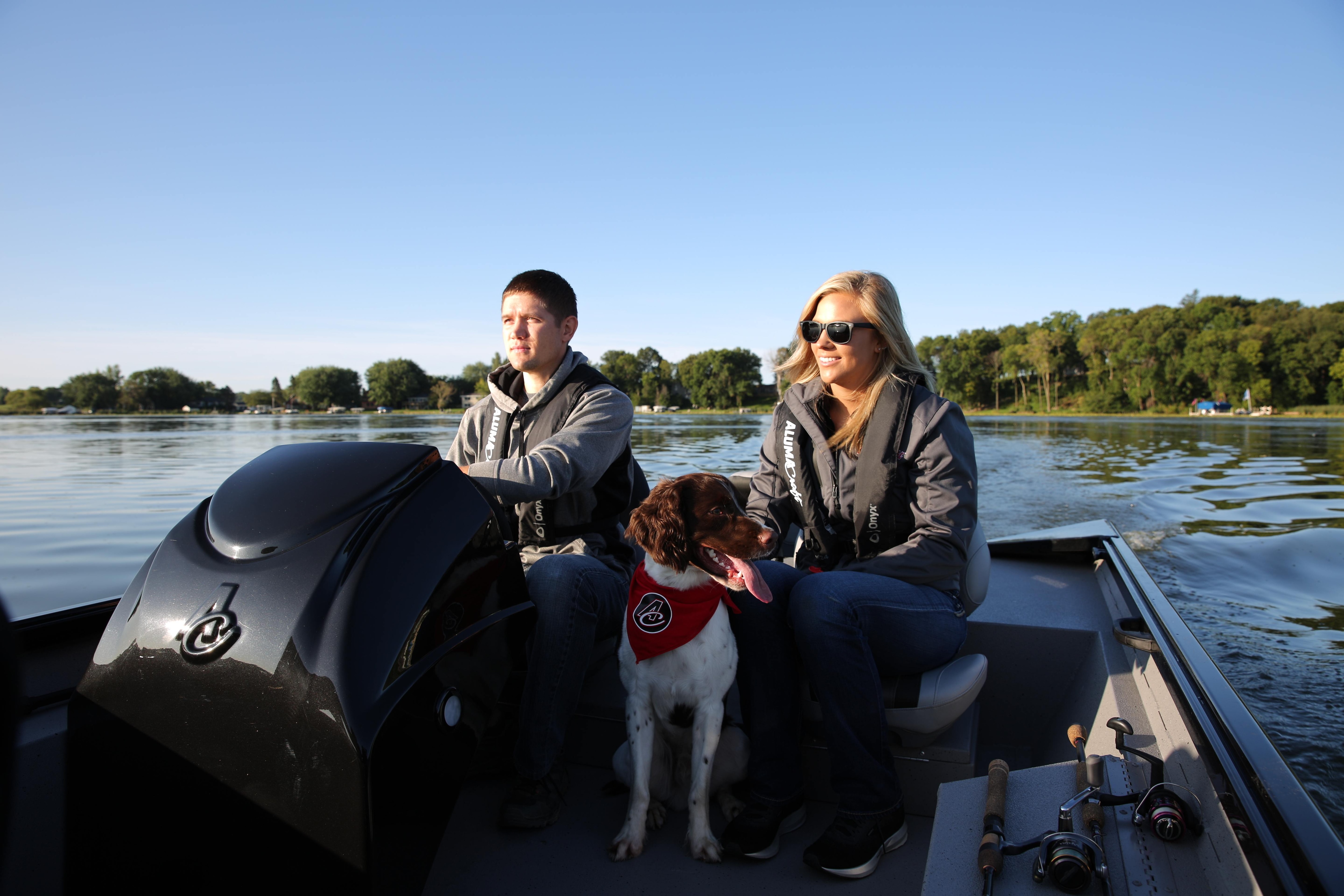 Couple with a dog on an Alumacraft fishing boat