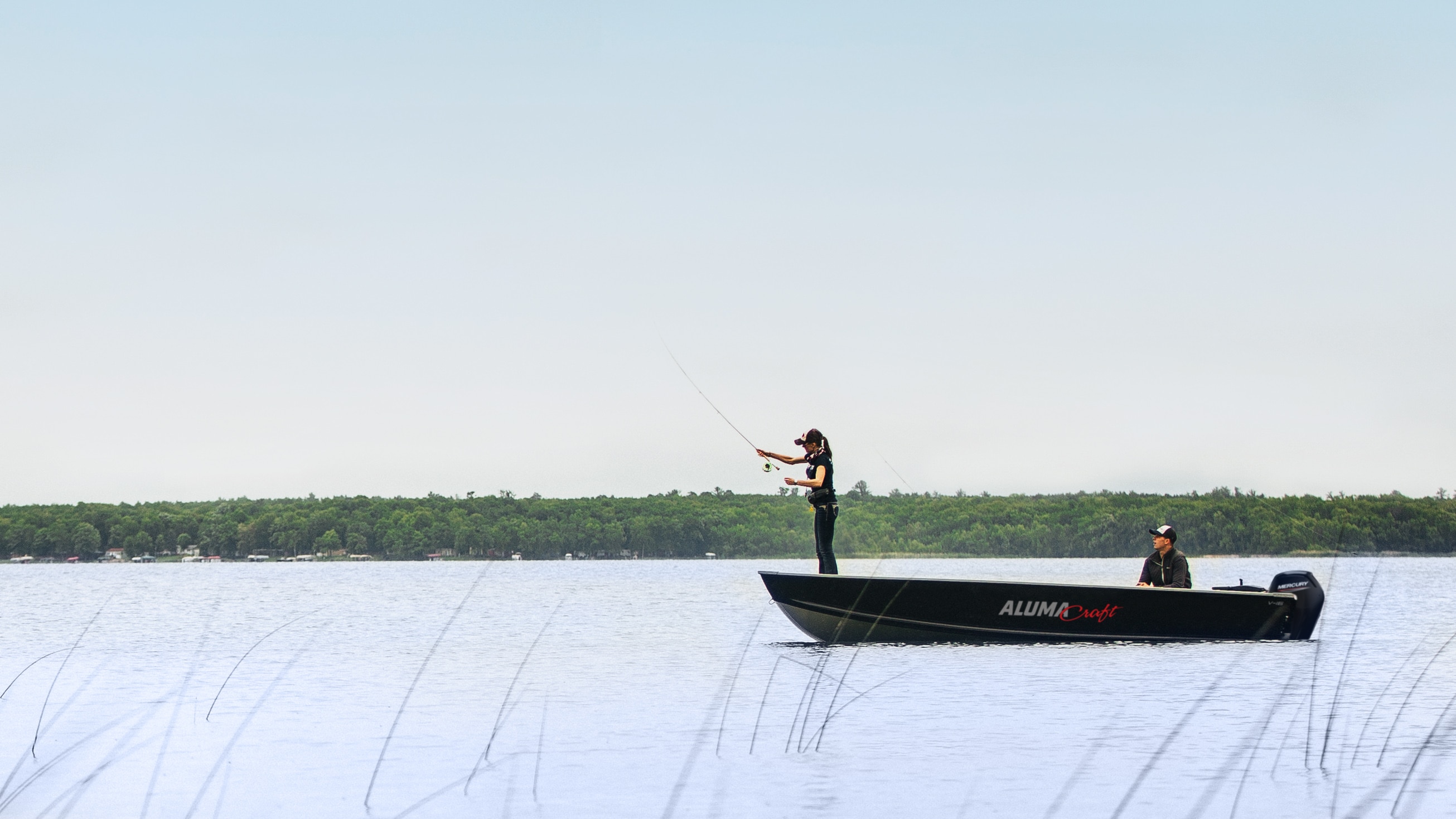 Homme pêchant à la mouche sur un bateau Alumacraft Hunt Utility