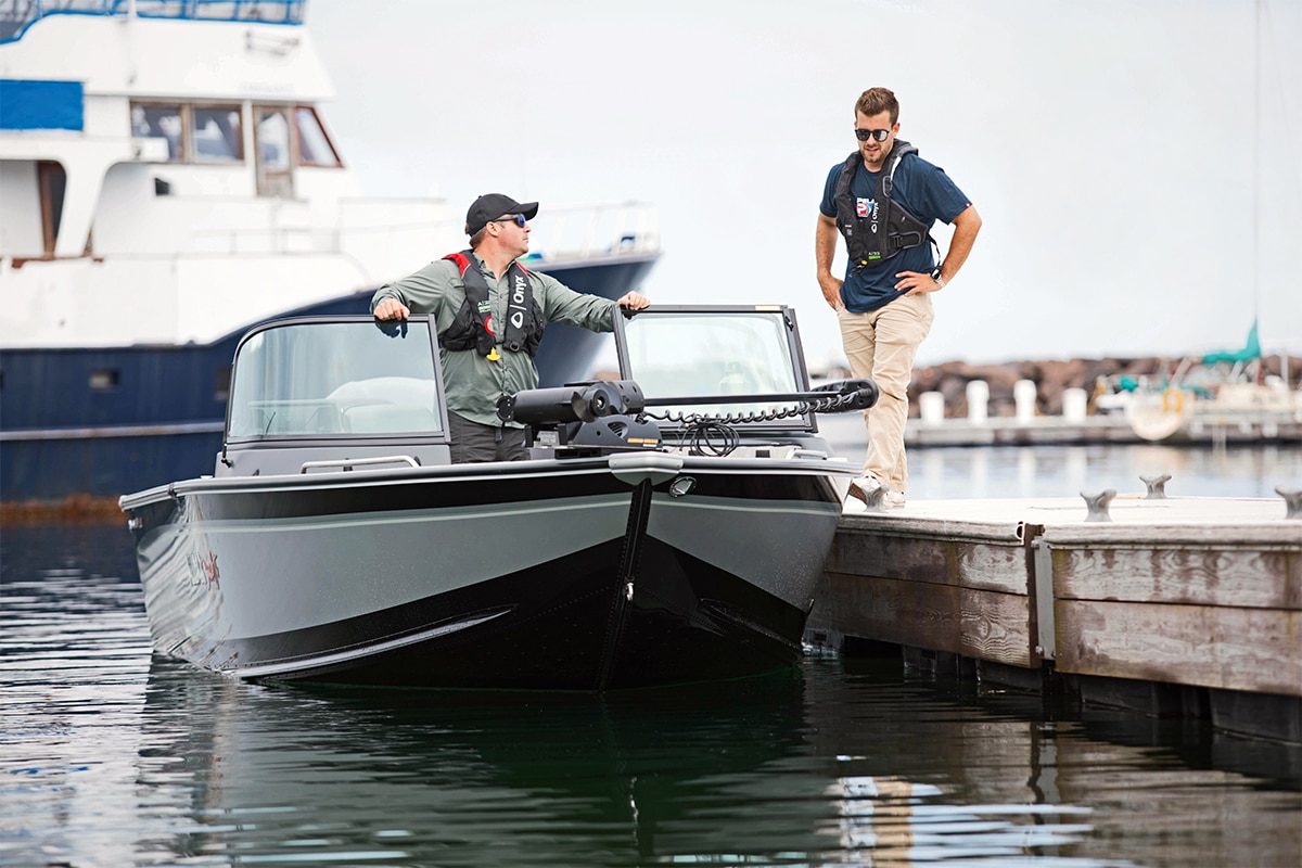Two men with chatting around a Silver Trophy Boat docked