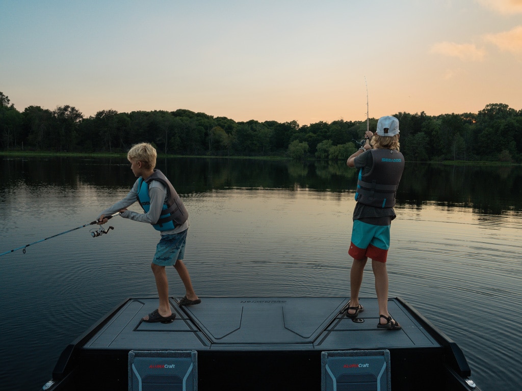 Two kids fishing from a 2023 Alumacraft Competitor aluminum fishing boat