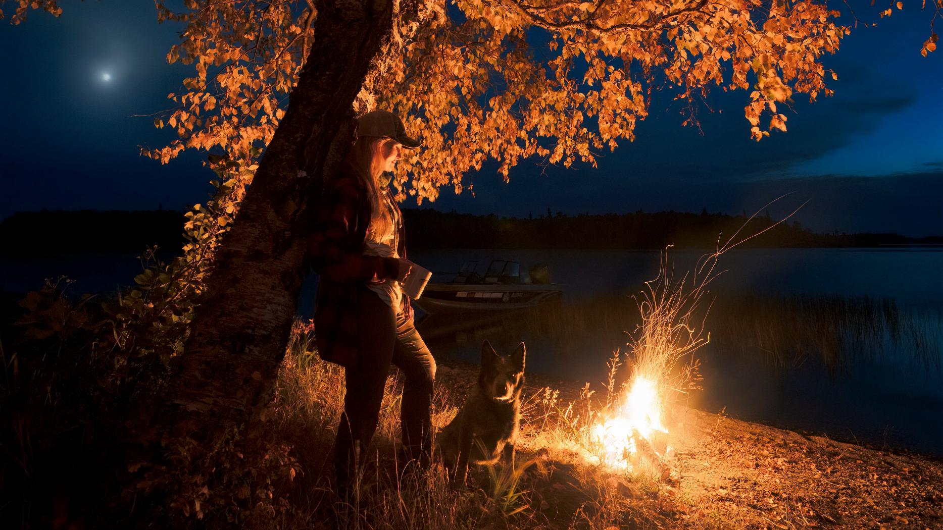Rebekka Redd and her dog around a campfire at night