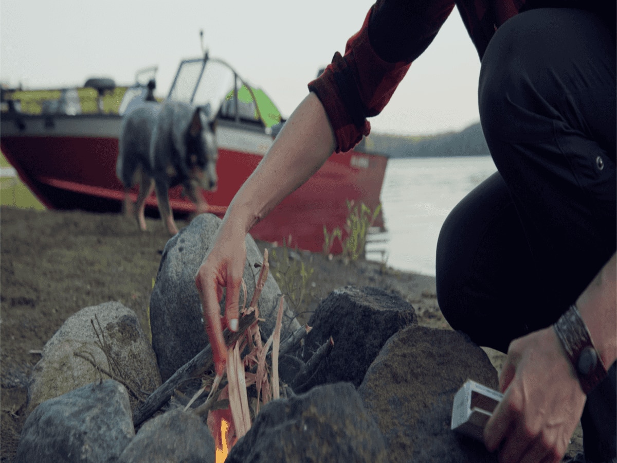 Rebekka Redd lighting a fire in front of an Alumacraft boat